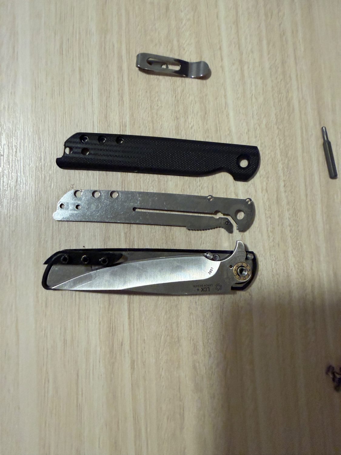 Folding knife components including blade, liner and custom handle components laid out before assembly