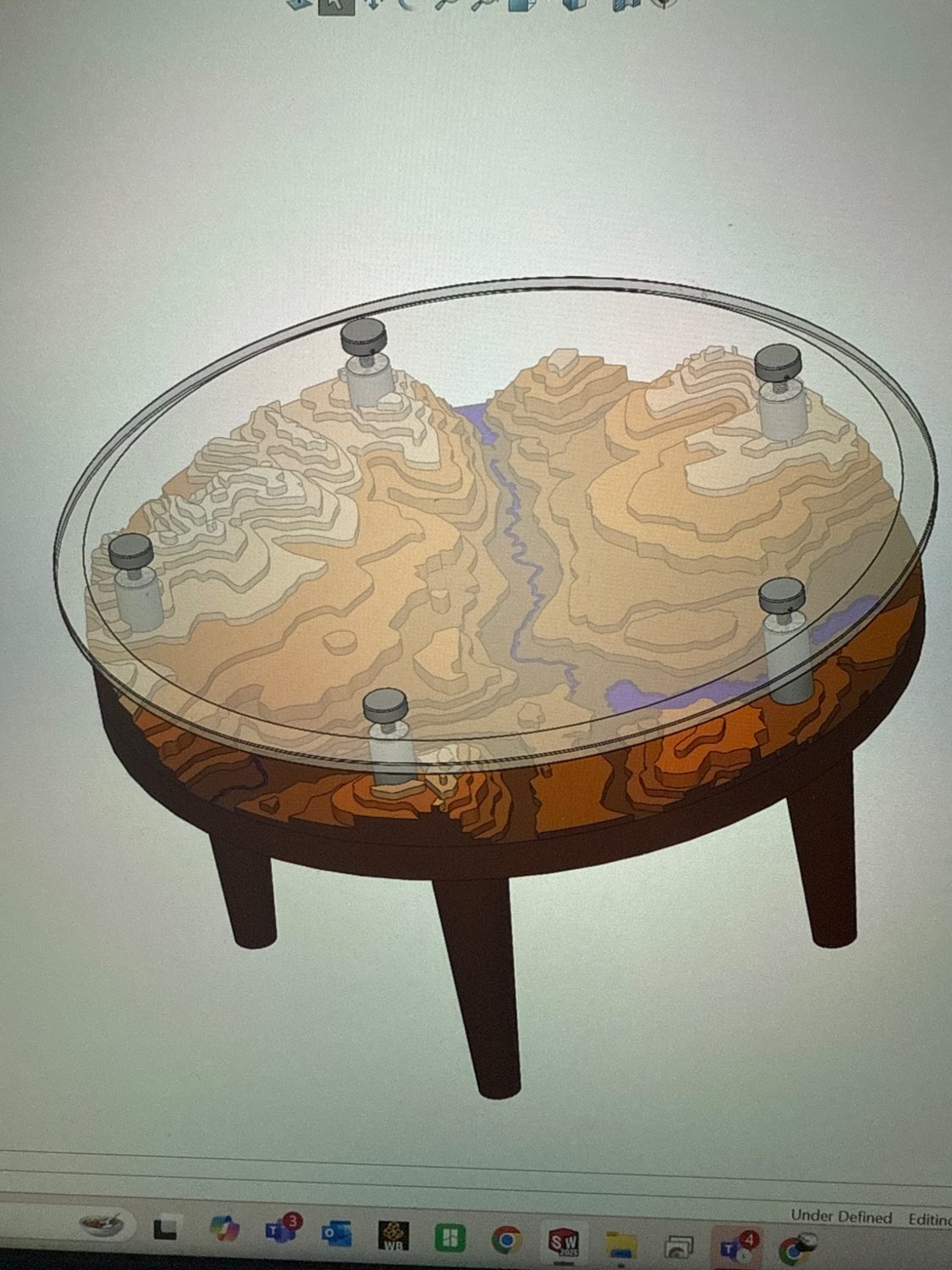 CAD rendering of round table with layered topographic landscape under a clear circular tabletop